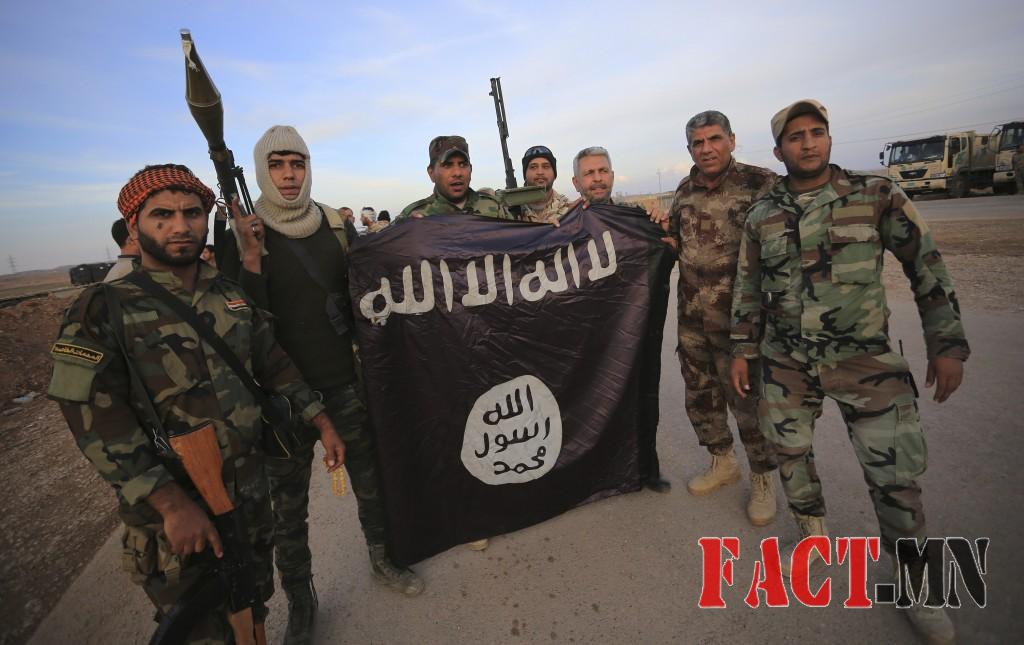 Iraqi Shi'ite fighters pose with an Islamic State flag which they pulled down on the front line in Jalawla