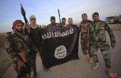 Iraqi Shi'ite fighters pose with an Islamic State flag which they pulled down on the front line in Jalawla