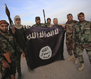 Iraqi Shi'ite fighters pose with an Islamic State flag which they pulled down on the front line in Jalawla