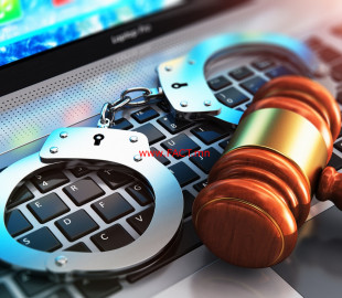 Handcuffs and judge mallet on laptop keyboard