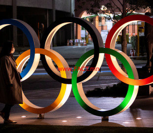 A woman wearing a protective face mask, following the outbreak of the coronavirus, walks past The Olympic rings in front of the Japan Olympics Museum in Tokyo